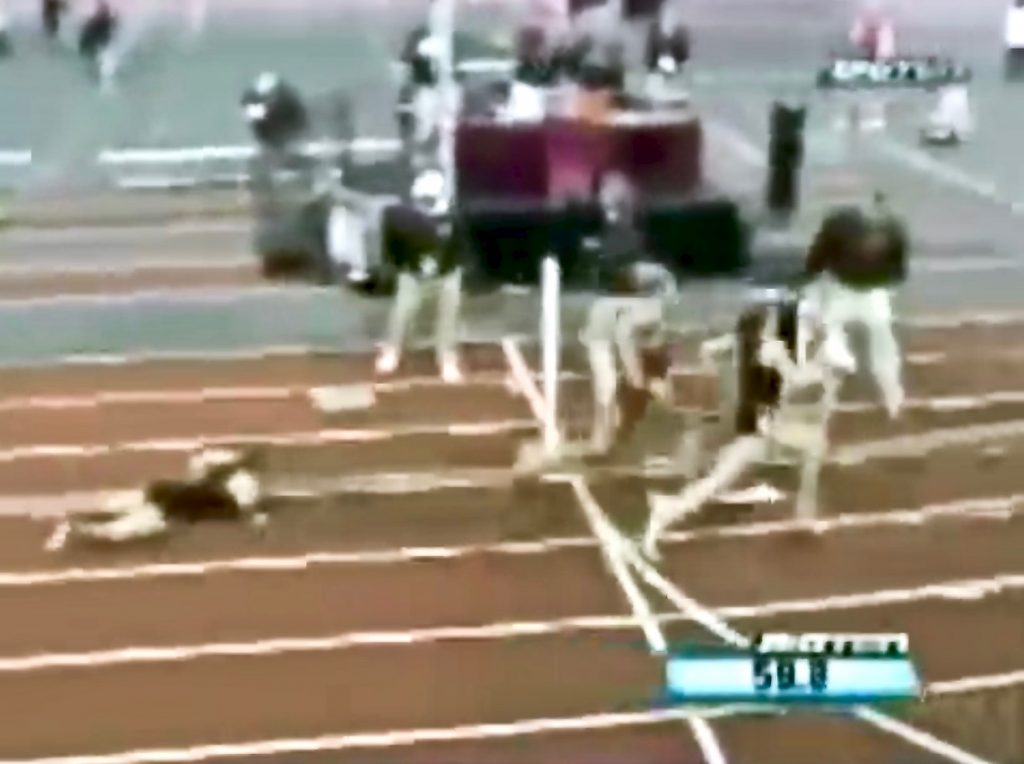 A screenshot of a grainy video of a runner on the ground as three runners race ahead of her
