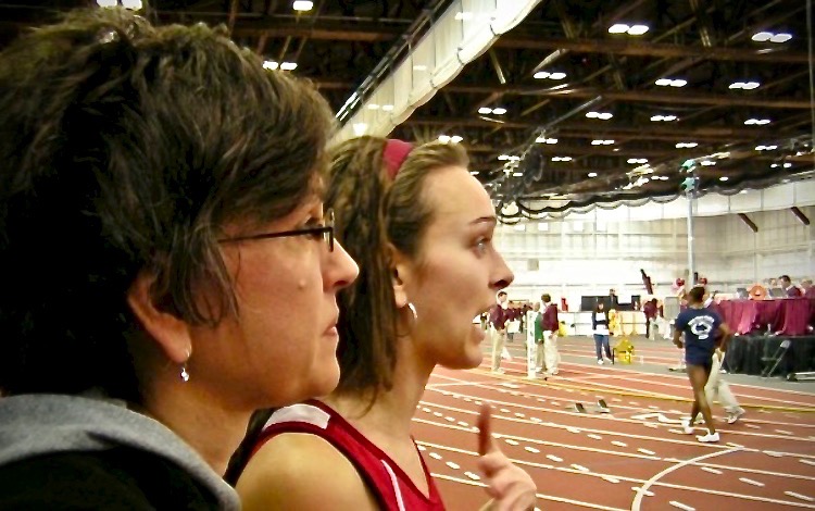 Two women look in the distance of an indoor track facility with surprised expressions 