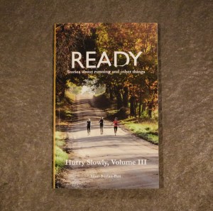 Image of book, Ready: Stories about running and other things, which has a photo of three women running on a dirt road in Bath, Michigan